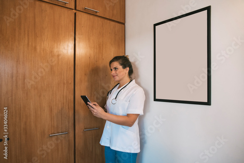 female doctor smiling with tablet in her office