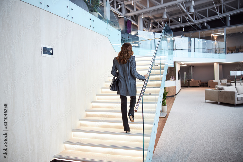 Elegant woman climbing stairs in business center