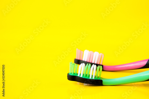 Two toothbrushes pink and green on a yellow background, oral hygiene