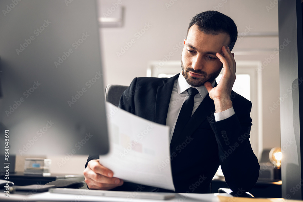 Concentrated Caucasian man reading documents in office Concentrated Caucasian man reading documents in office