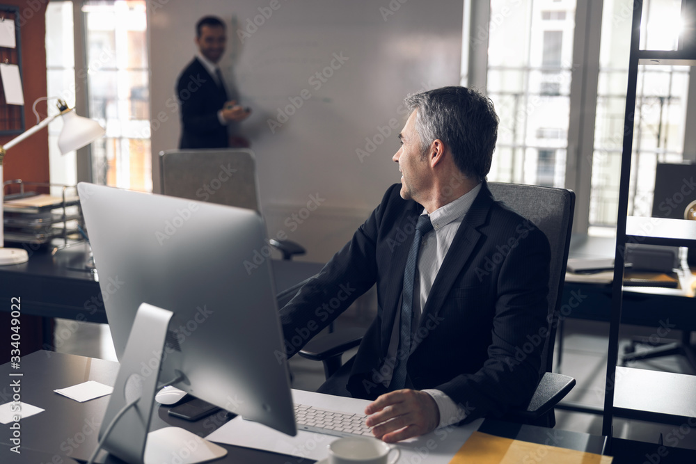 Serious office worker in suit talking to his colleague indoors Serious office worker in suit talking to his colleague indoors