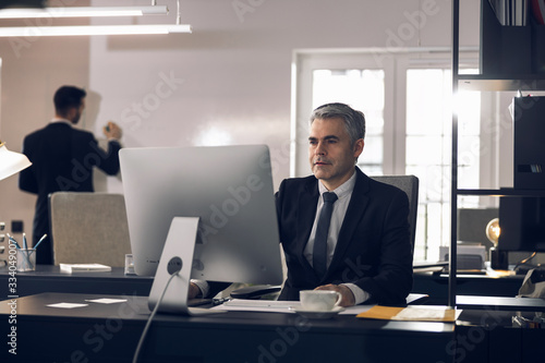 Mature office worker in suit working at computer indoors