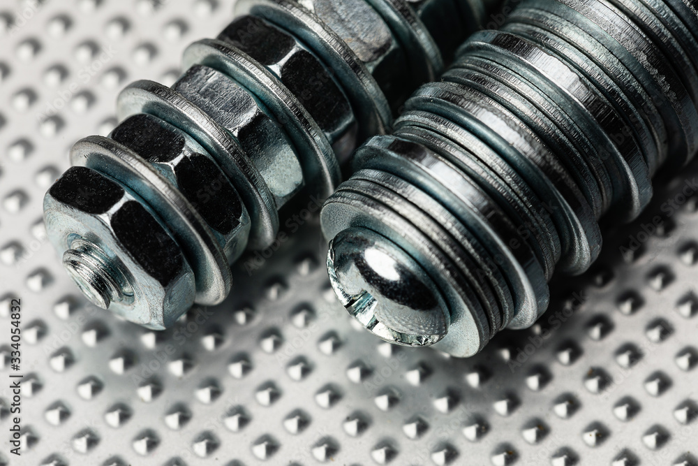 cool blue toned macro of small bolts with nuts and washers on an industrial steel surface. Strong Contrast cool blue toned macro of small bolts with nuts and washers on an industrial steel surface. Strong Contrast