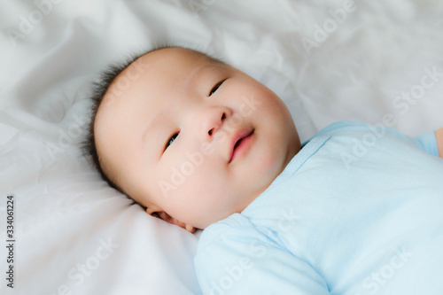 happy and enjoy Portrait of a newborn Asian baby boy on the bed ,a dummy in his mouth, Charming