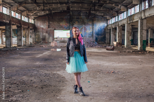 Portrait of a young girl with pink hair standing inside of collapsed building surrounded by ruins