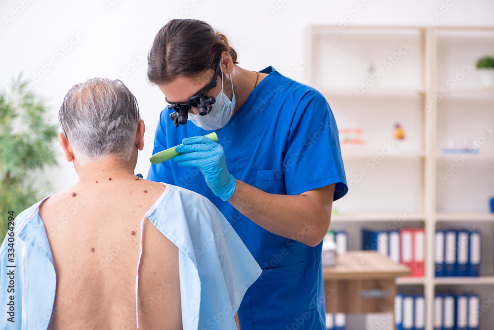 Fototapeta premium Old man visiting young male doctor dermatologist