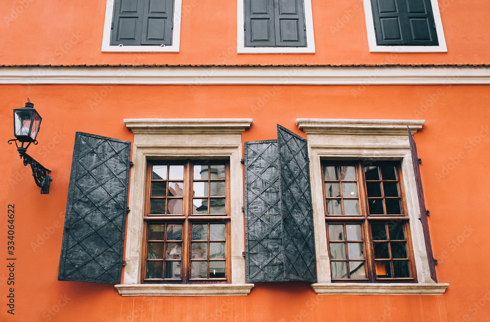 Open metal shutters on the old beautiful windows. Orange facade of the building of the Armenian courtyard in Lviv.