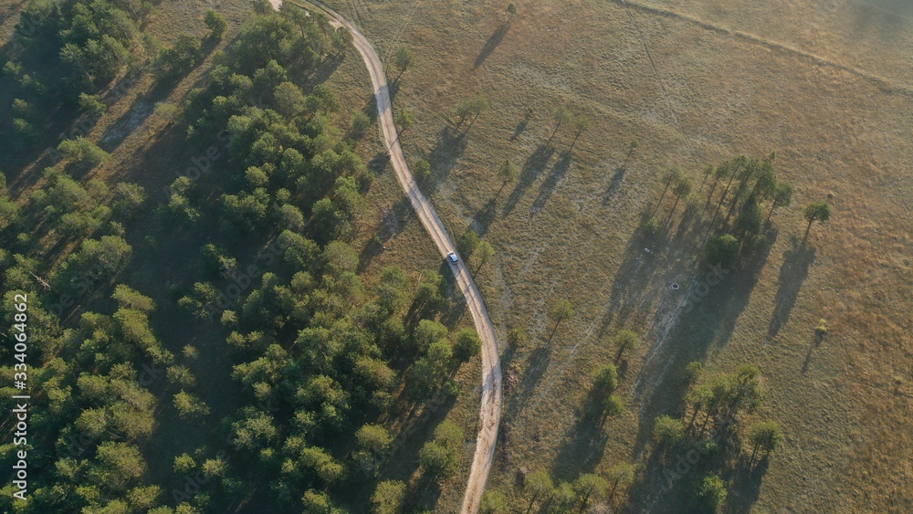 Aerial top down view of car driving on rural road, path near forest. Sunrise in village Grahovo, Montenegro. Countryside. Rural landscape. Aerial top down view of car driving on rural road, path near forest. Sunrise in village Grahovo, Montenegro. Countryside. Rural landscape.