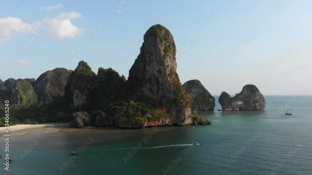 Sunset ocean white sand tropical beach at railey phra nang beach thailand drone footage. Limestone cliffs rocks in the andaman sea torquiose vacation with long tail boats. Sunset ocean white sand tropical beach at railey phra nang beach thailand drone footage. Limestone cliffs rocks in the andaman sea torquiose vacation with long tail boats.