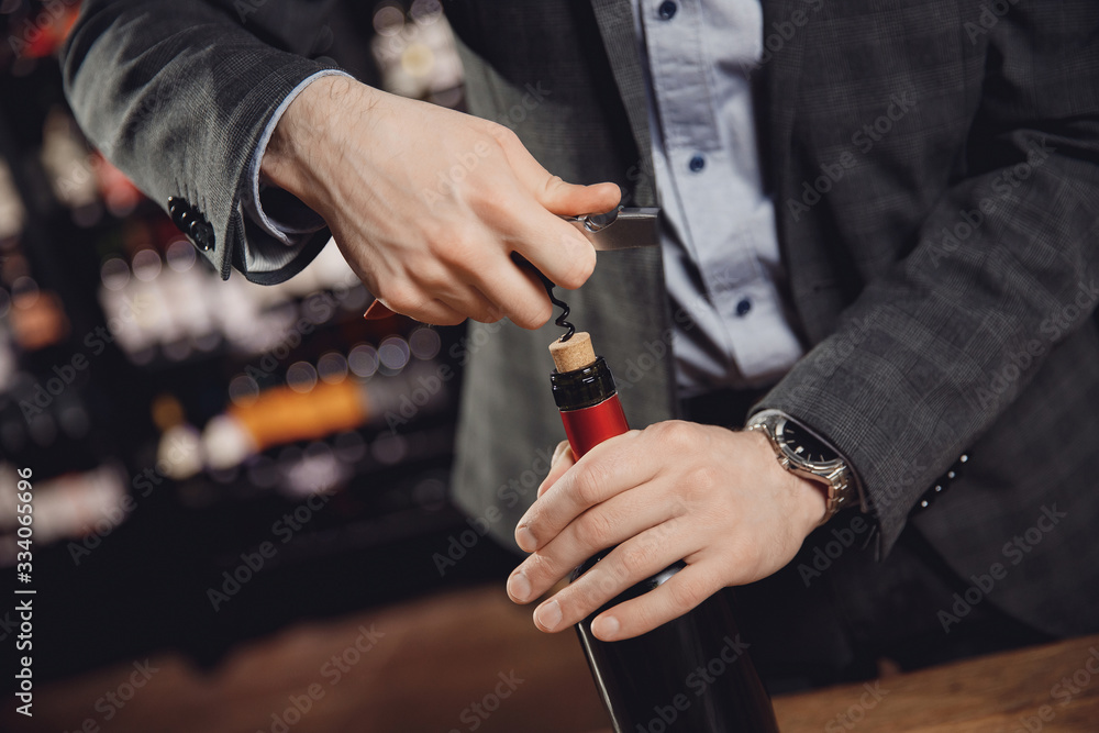 Sommelier opens cork of bottle of red wine with corkscrew