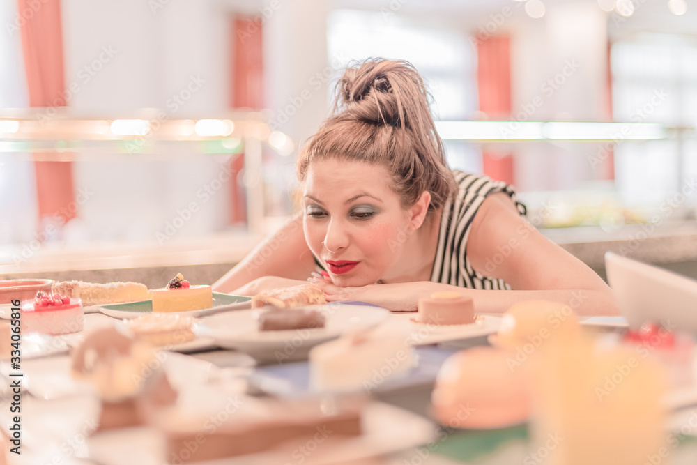 woman looking at an assortment of desserts with desire woman looking at an assortment of desserts with desire