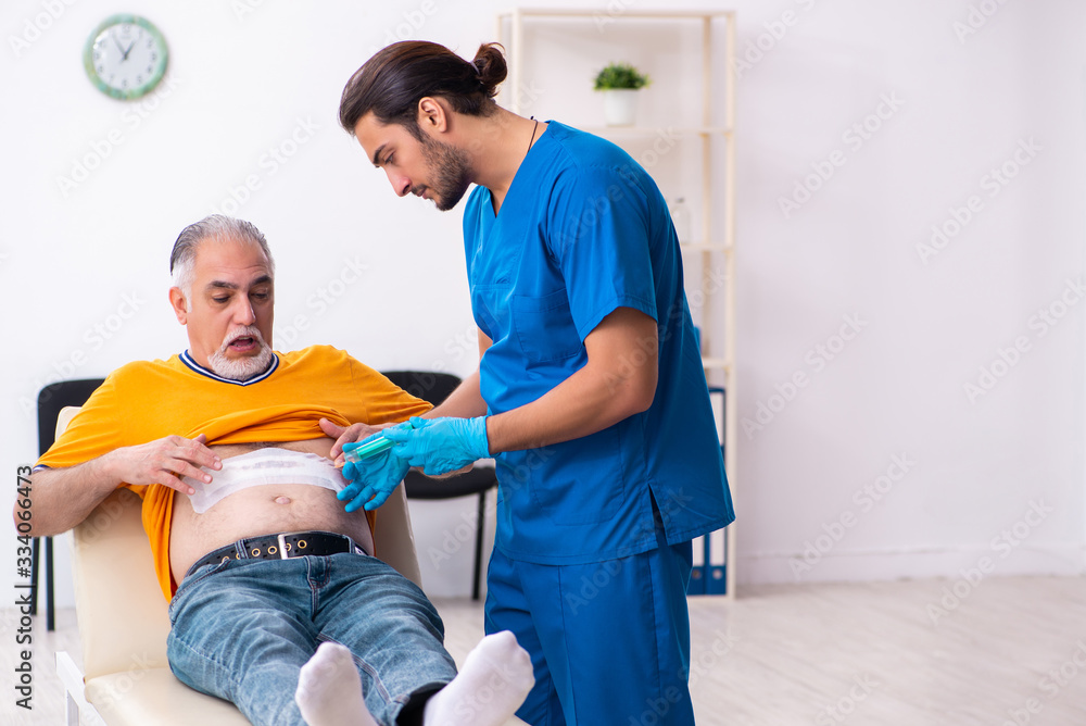 Fototapeta premium Old man visiting young male doctor