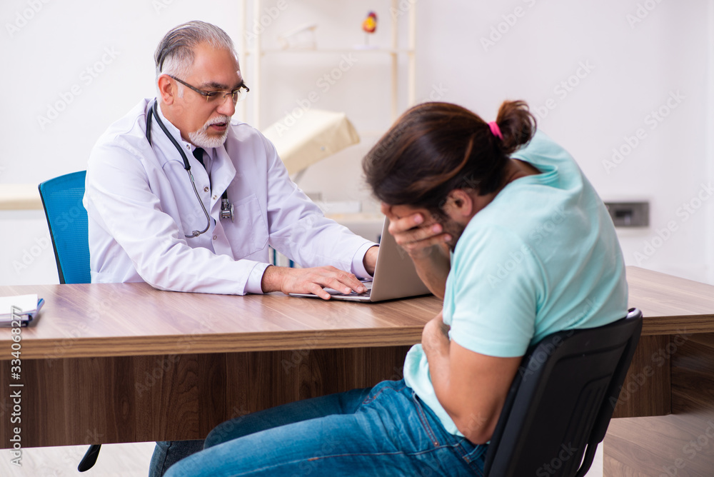 Fototapeta premium Injured young man visiting old doctor