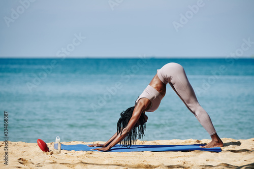 Fit young woman standing in downward facing dog to rest between difficult asanas Fototapeta