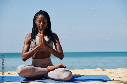Принти на полотні Beautiful slim young woman meditating in lotus position on the beach
