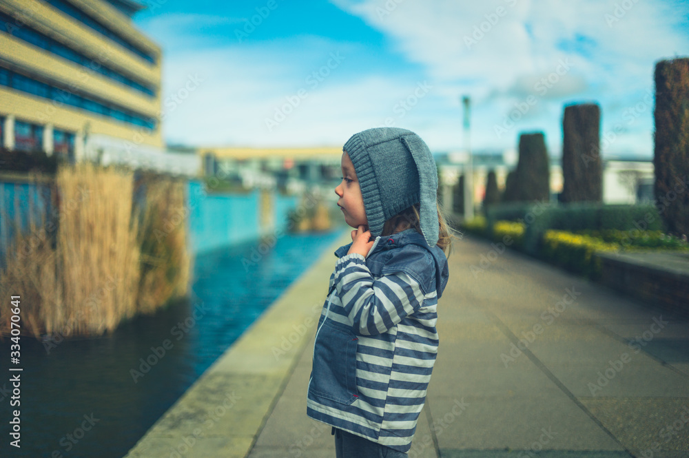 Fototapeta premium Little preschooler standing by artificial pond in the city