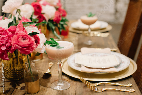 A table setting ready for a celebration decorated with pink and white florals and showcasing a signiture creamy cocktail