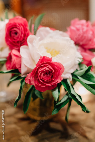 White and pink colored peonies and ranunculuses in mercury glass vase as wedding table center pieces