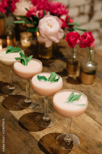 Light pink creamy alcoholic cocktails garnished with mint on a rustic surface