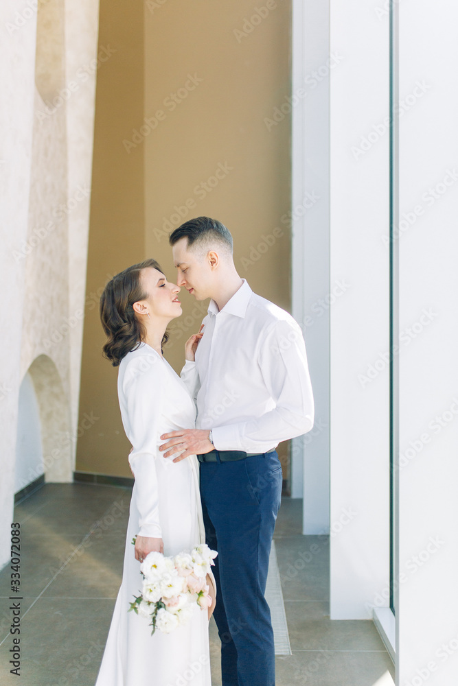 The bride and groom's romantic photo shoot. The newlyweds are happy together. Stylish modern couple in a light interior. The bride and groom's romantic photo shoot. The newlyweds are happy together. Stylish modern couple in a light interior.