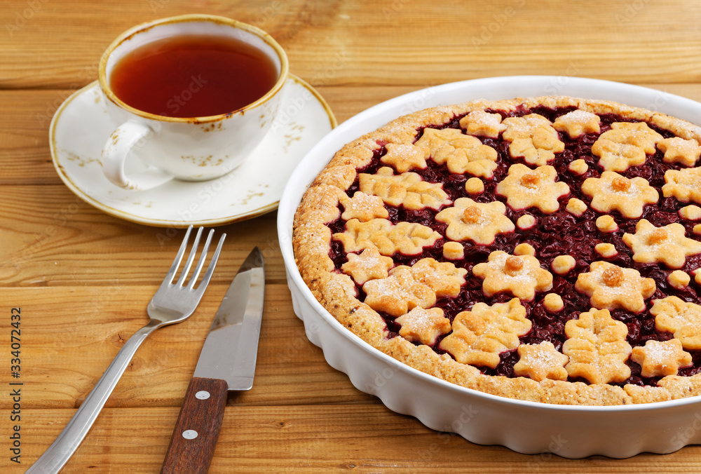 Homemade cherry pie crostata and cup of tea on white wooden table. Angle view. Homemade cherry pie crostata and cup of tea on white wooden table. Angle view.