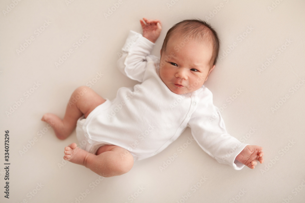 Newborn baby boy in white body on bed Newborn baby boy in white body on bed
