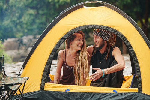 Cheerful man resting in tent with his wife or girfriend and telling funny stories to make her laugh photo