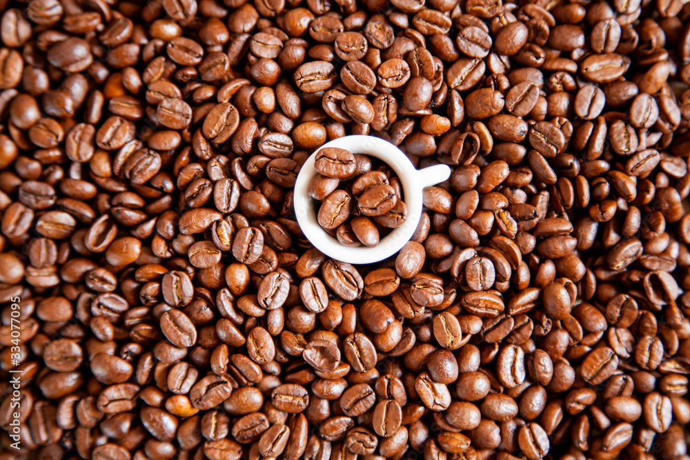 Fototapeta premium A small white cup of coffee stands on coffee beans.