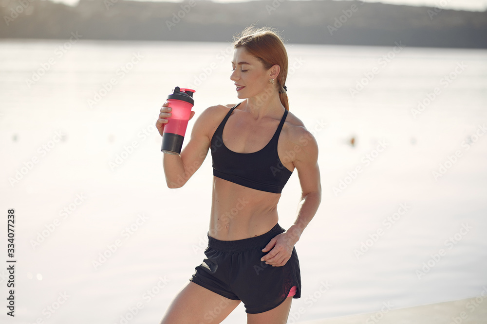 Girl training. Woman in a sports shorts. Redheads girl in a summer park Girl training. Woman in a sports shorts. Redheads girl in a summer park