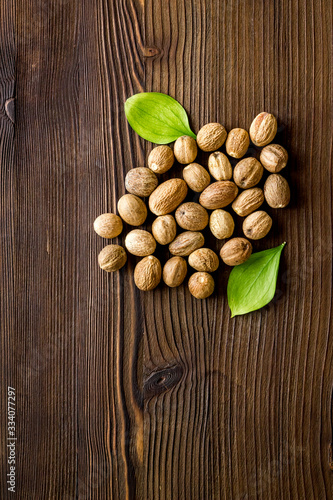 Nutmeg - whole nuts near leves - on wooden background top-down