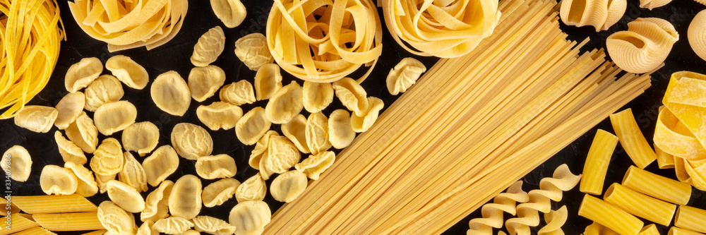 Italian pasta, a flat lay panoramic overhead shot of many different pasta sorts on a black background, food texture Italian pasta, a flat lay panoramic overhead shot of many different pasta sorts on a black background, food texture