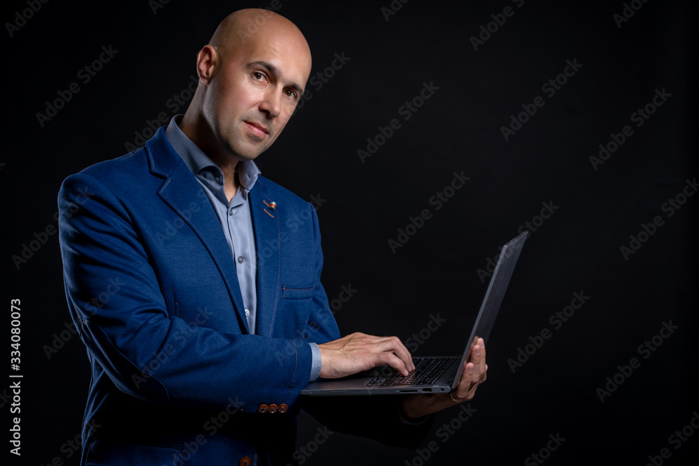 Portrait of man with laptop in studio on black background