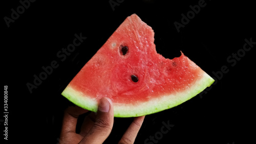 The person bitten the watermelon isolated by the black background