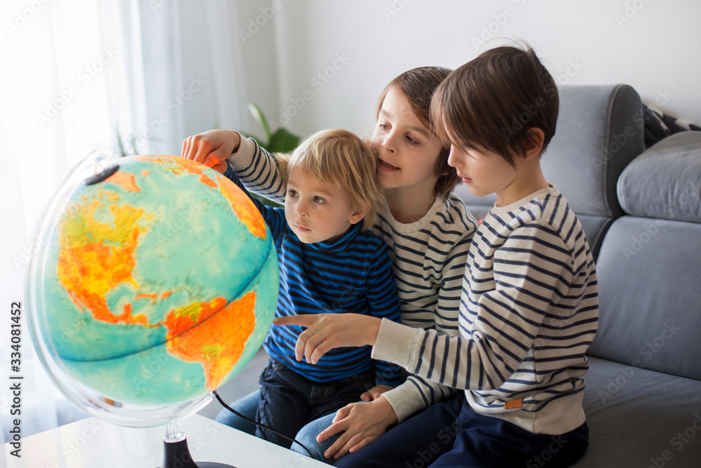 Little children, brothers, looking at illuminated globe, exploring Little children, brothers, looking at illuminated globe, exploring