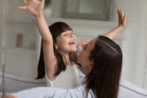 Overjoyed little girl have fun playing with young mom at home on leisure family weekend, happy small preschooler daughter engaged in funny activity, enjoy playtime with smiling loving mother