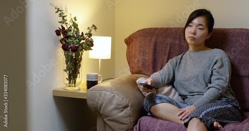 Bored Asian Woman Watching TV In Self-Isolation During Corona Virus B photo