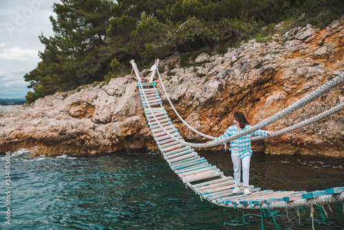 Vászonkép woman crossing suspension bridge sea on background