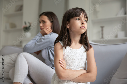 Offended young mother and little preschooler daughter sit separately ignore talking after fight, mad mom and small girl child avoid communication, have family misunderstanding, generation gap concept