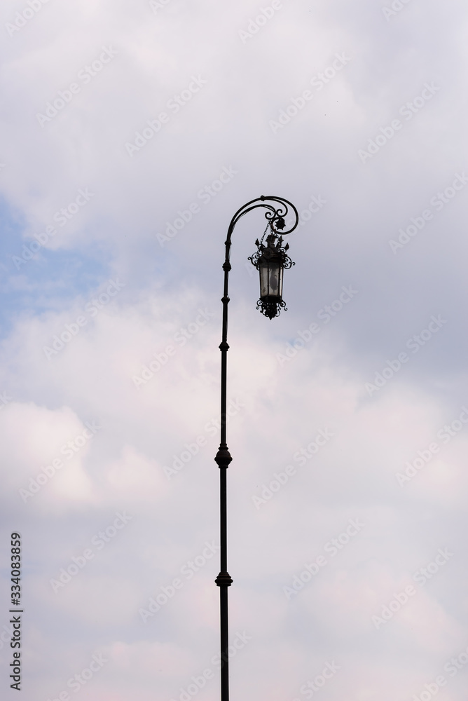 forged old lantern against the sky with clouds forged old lantern against the sky with clouds