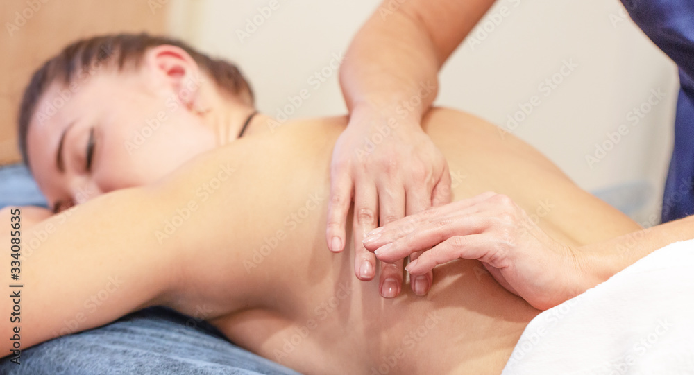 Massage therapist doing massage on the back of young girl