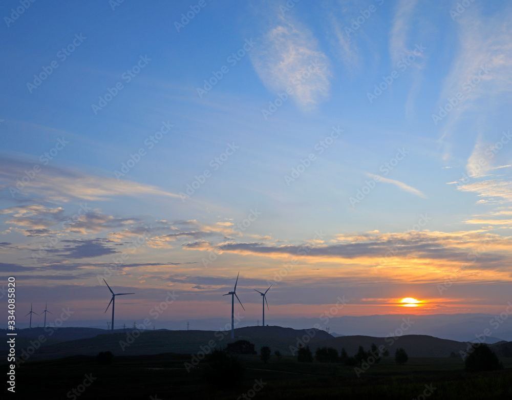 Obraz premium The windmill in the sunset, on the hillside
