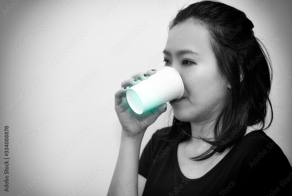 Asian young woman drinking a fresh white paper cup of water or other beverage.bllack and white tone Asian young woman drinking a fresh white paper cup of water or other beverage.bllack and white tone