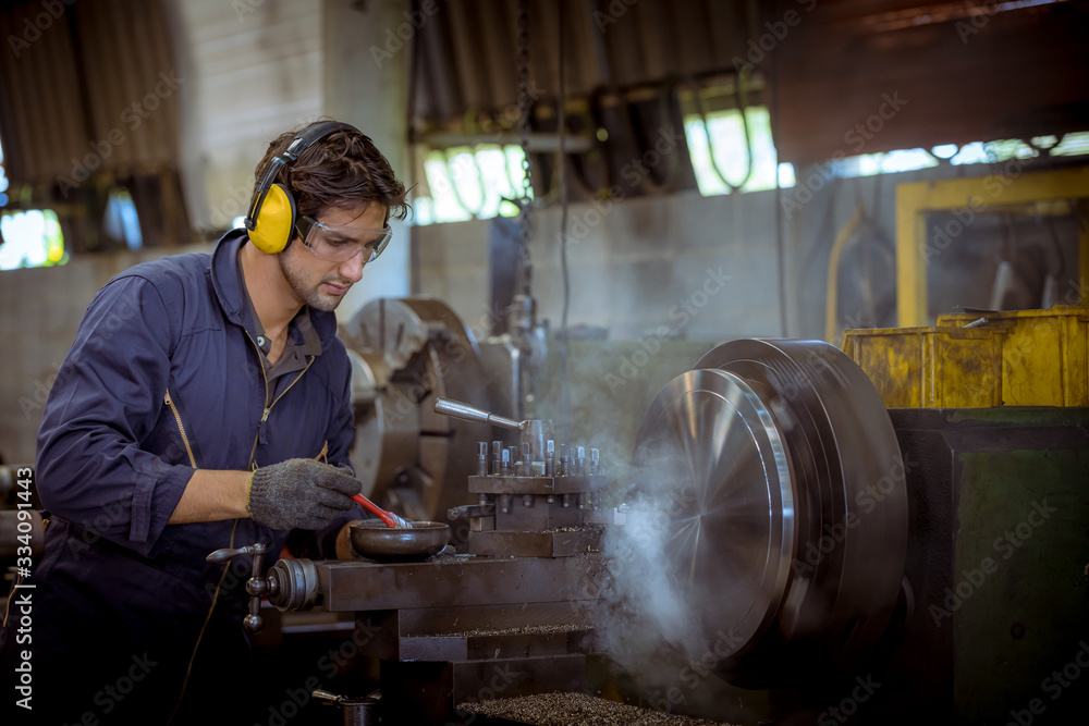 The Industry worker wearing safety uniform used lubricant oil control operating lathe grinding machine working in industry factory. The Industry worker wearing safety uniform used lubricant oil control operating lathe grinding machine working in industry factory.