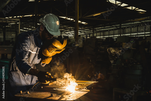 Industrial worker welding metal with many sharp sparks