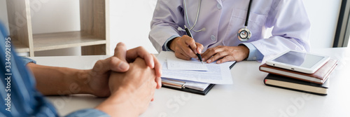 patient listening intently to a male doctor explaining patient symptoms or asking a question as they discuss paperwork together in a consultation photo