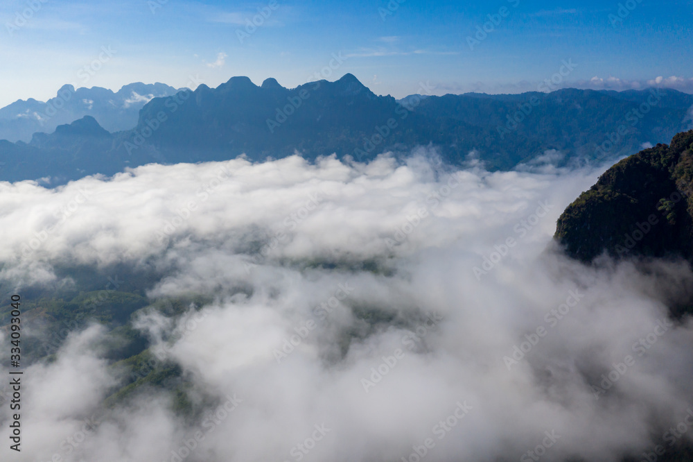 Aerial view of early morning clouds and towering limestone mountains in rural Thailand