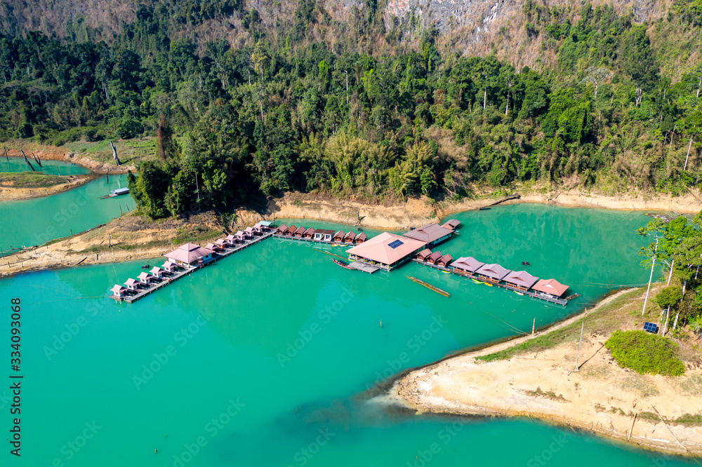 Aerial view of a floating wooden rafthouse on a huge lake surrounded by jungle (Cheow Lan Lake, Khao Sok, Thailand)