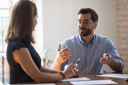 Business entities gathered together for negotiations, meeting lead by Caucasian businessman team leader express opinion point of view. Businesspeople sit at desk in boardroom solving issues concept