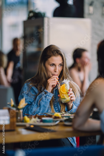 portrait of a beautiful european girl sitting in a restaurant and drinking cocktail