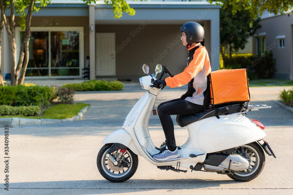 Asian man courier on scooter delivering food in town streets with a hot